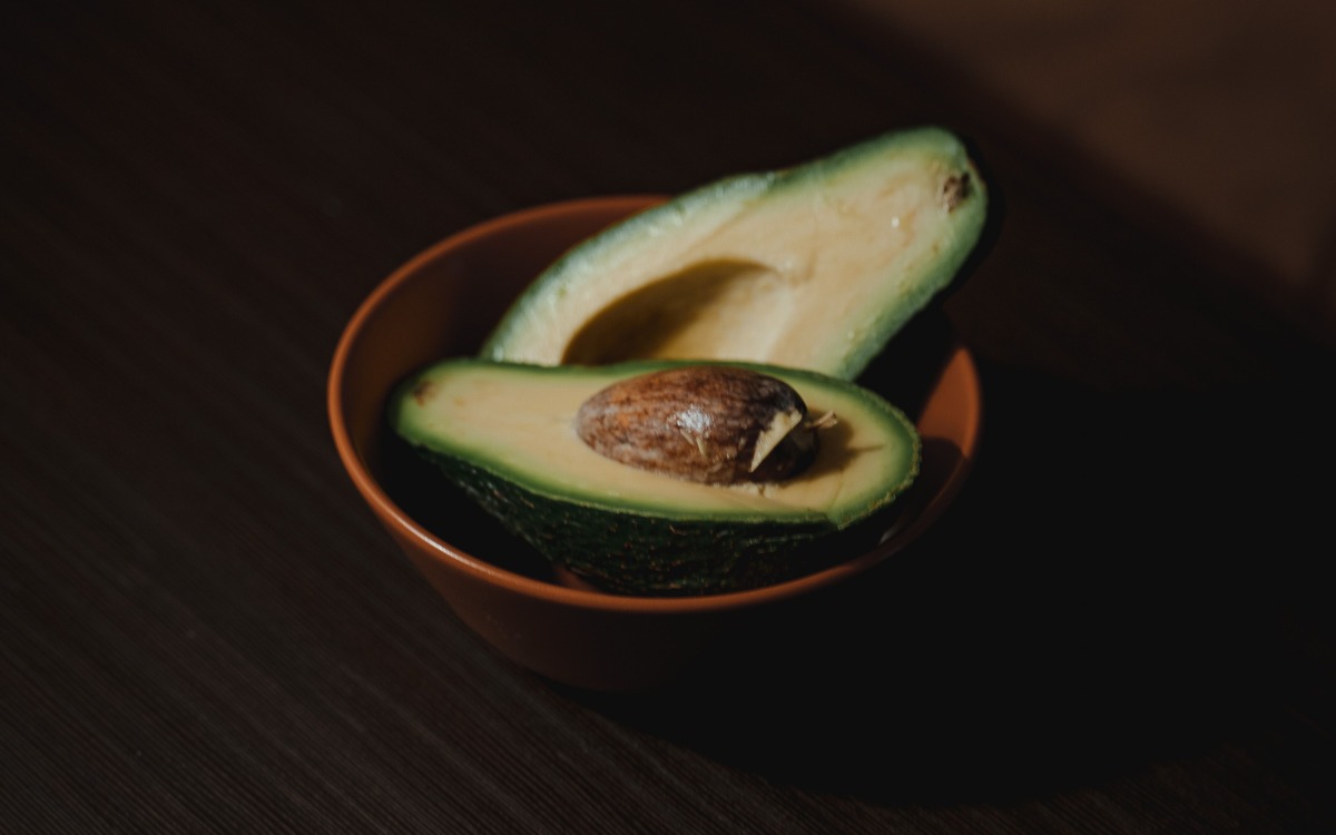 Whole and halved ripe avocados arranged on a kitchen cutting board