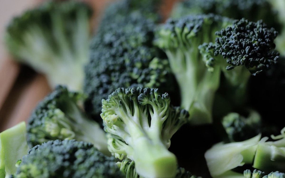 Fresh broccoli florets cut on a wooden board and ready for blanching and freezing