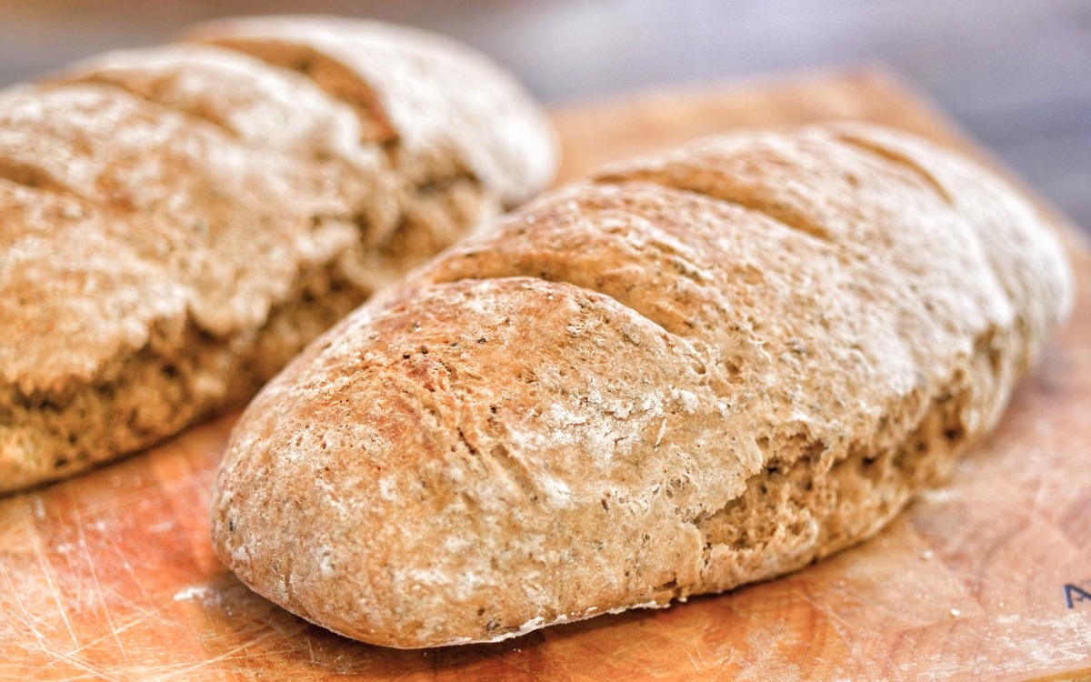 Freshly baked loaves of bread cooling on a wooden board