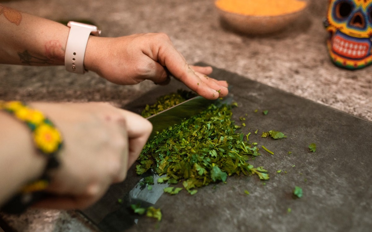 Fresh herbs being chopped on a wooden cutting board during meal preparation