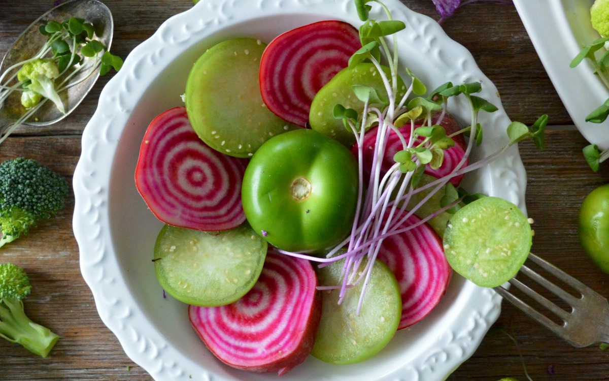 Colorful vegetables arranged in a bowl and around a kitchen table