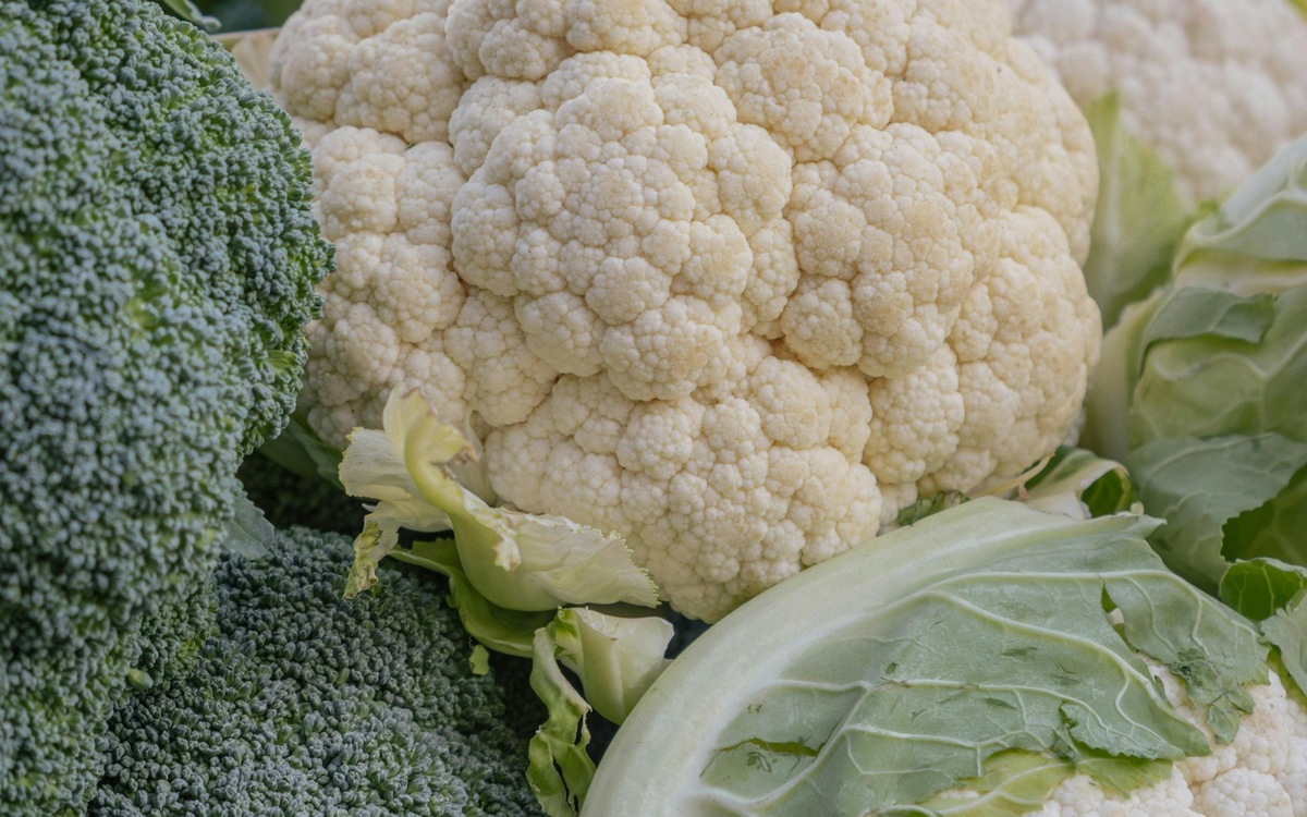 Fresh broccoli and cauliflower piled together at a produce market