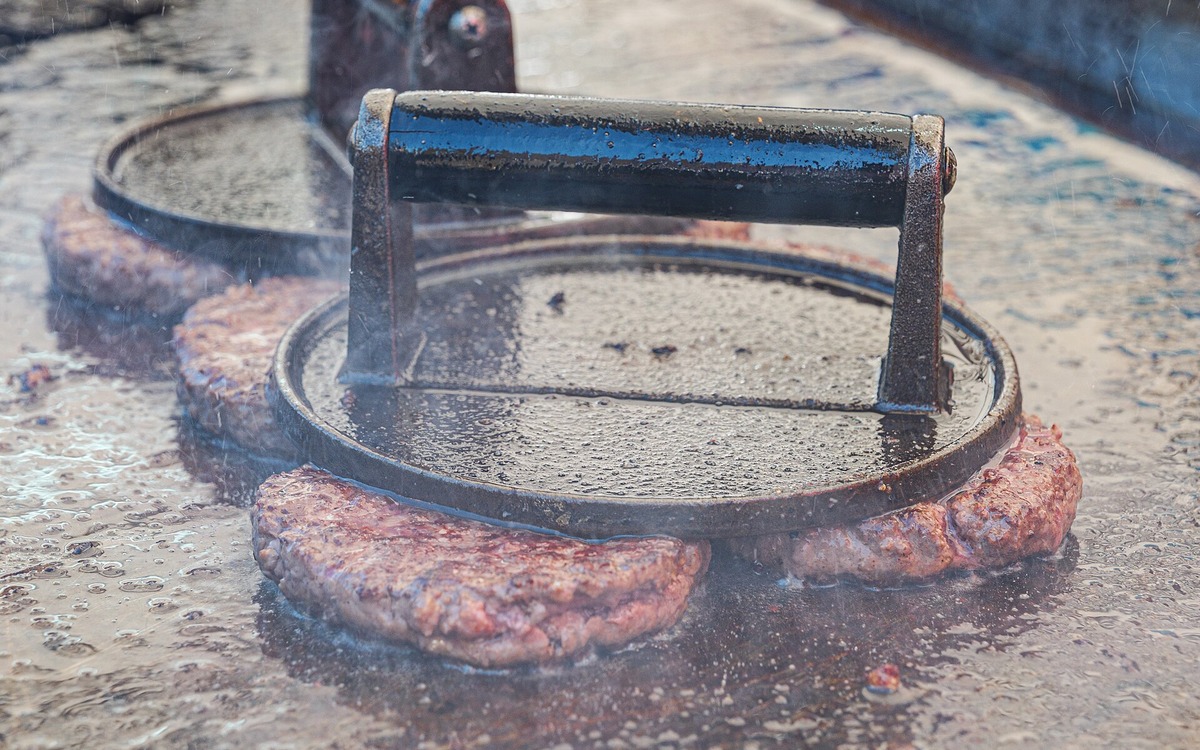 Raw beef being handled on a clean preparation surface before cooking