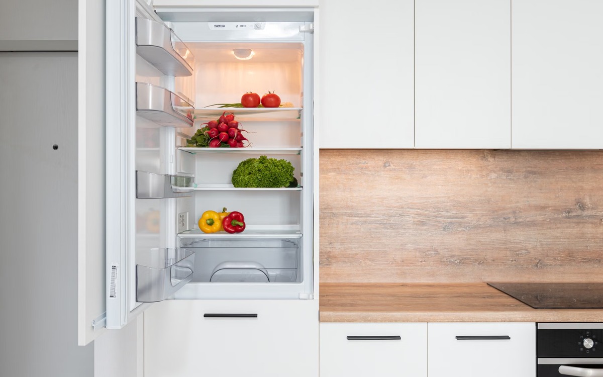 Fresh vegetables including leafy greens stored inside a clean refrigerator