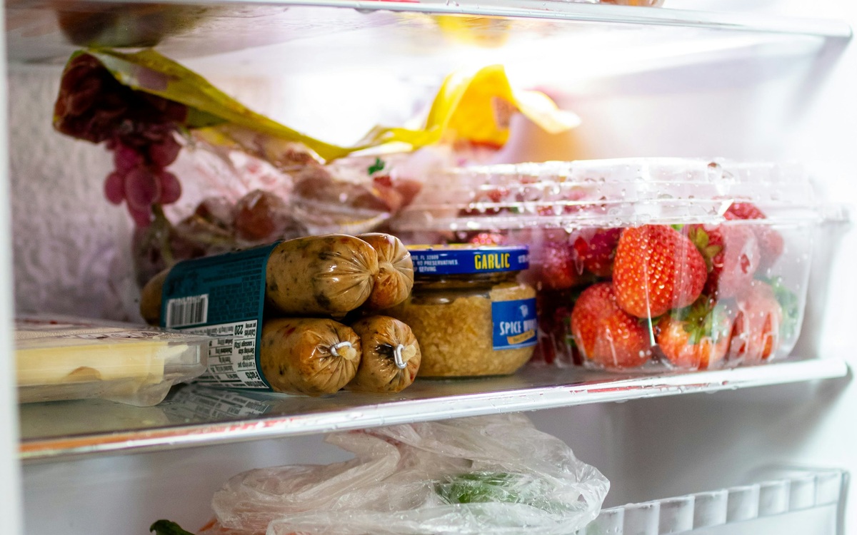 A stocked refrigerator with vegetables, eggs, and prepared food