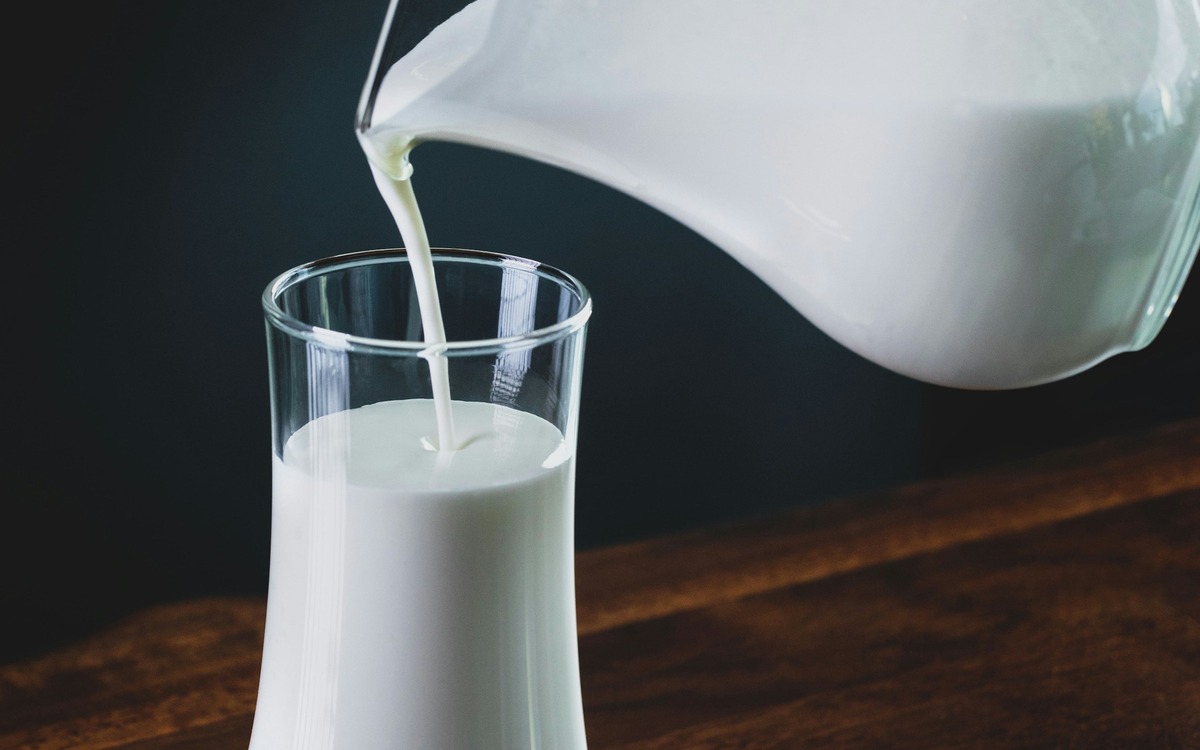 Milk being poured from a carton into a measuring cup