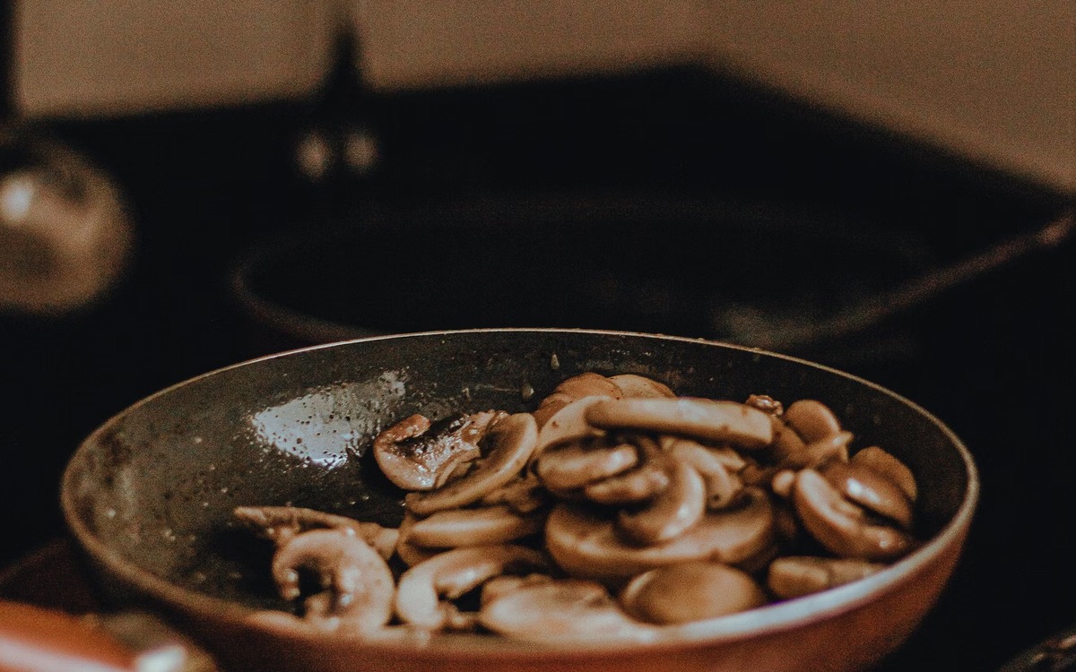 Sliced edible mushrooms browning in a frying pan
