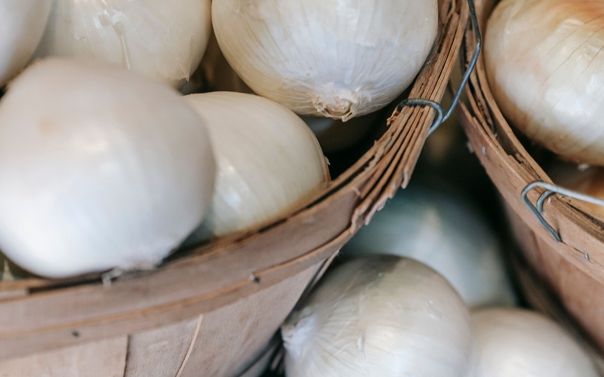 Fresh whole onions displayed in baskets at a produce market