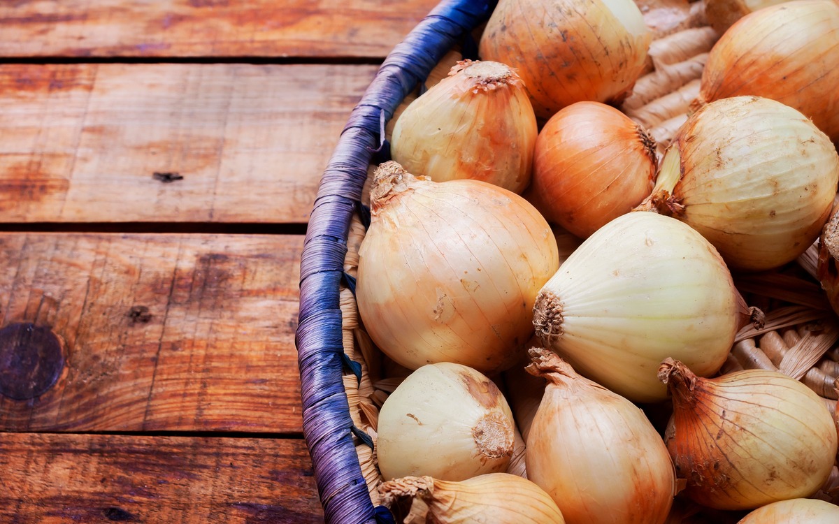 Whole yellow onions resting in a ventilated woven basket