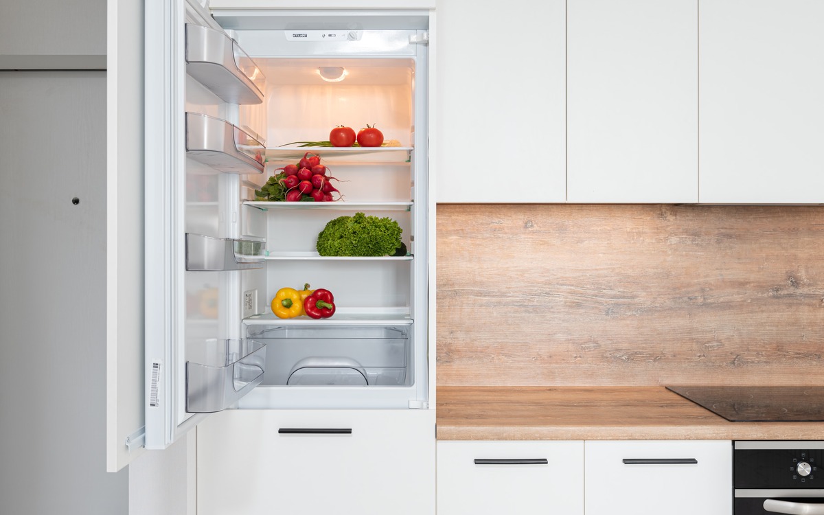Fresh tomatoes and other produce stored inside an open refrigerator