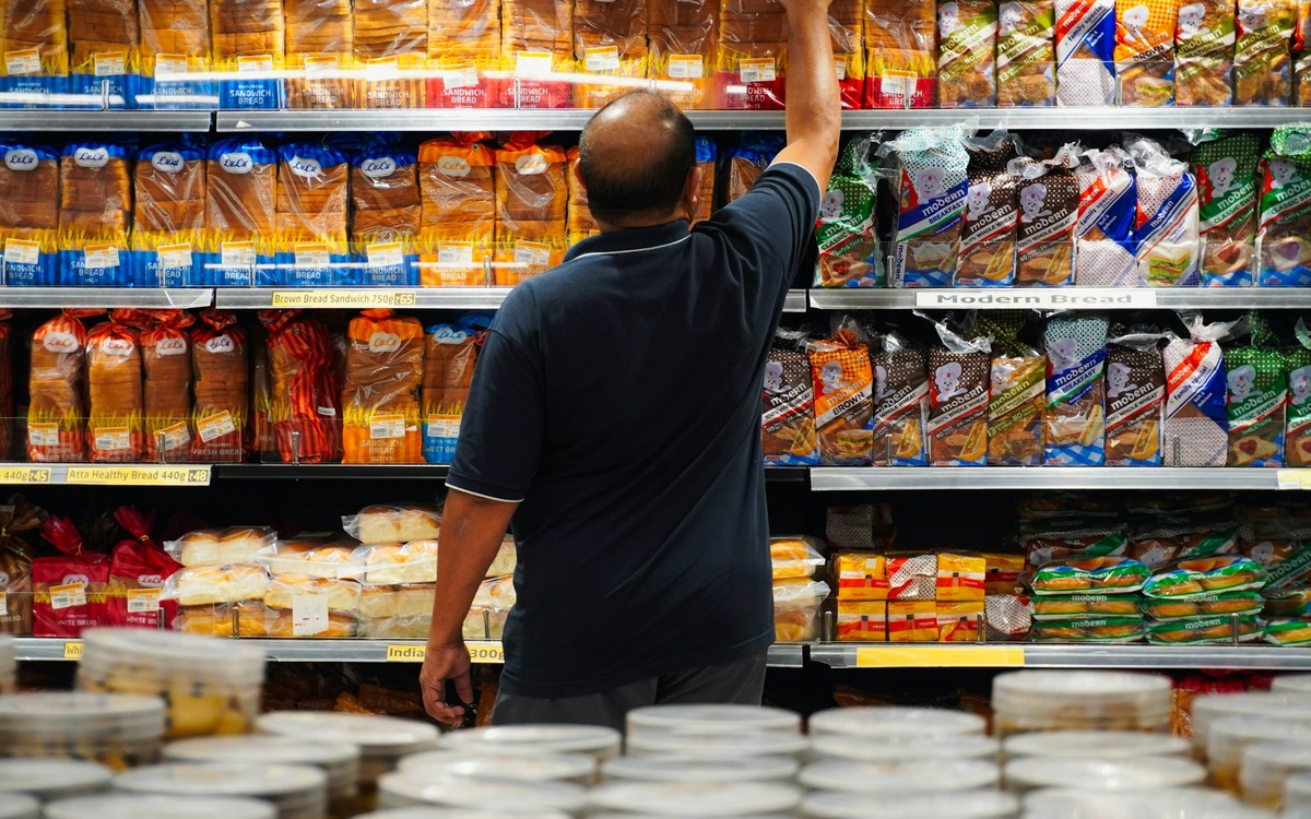 Shopper reaching for packaged bread on a grocery store shelf